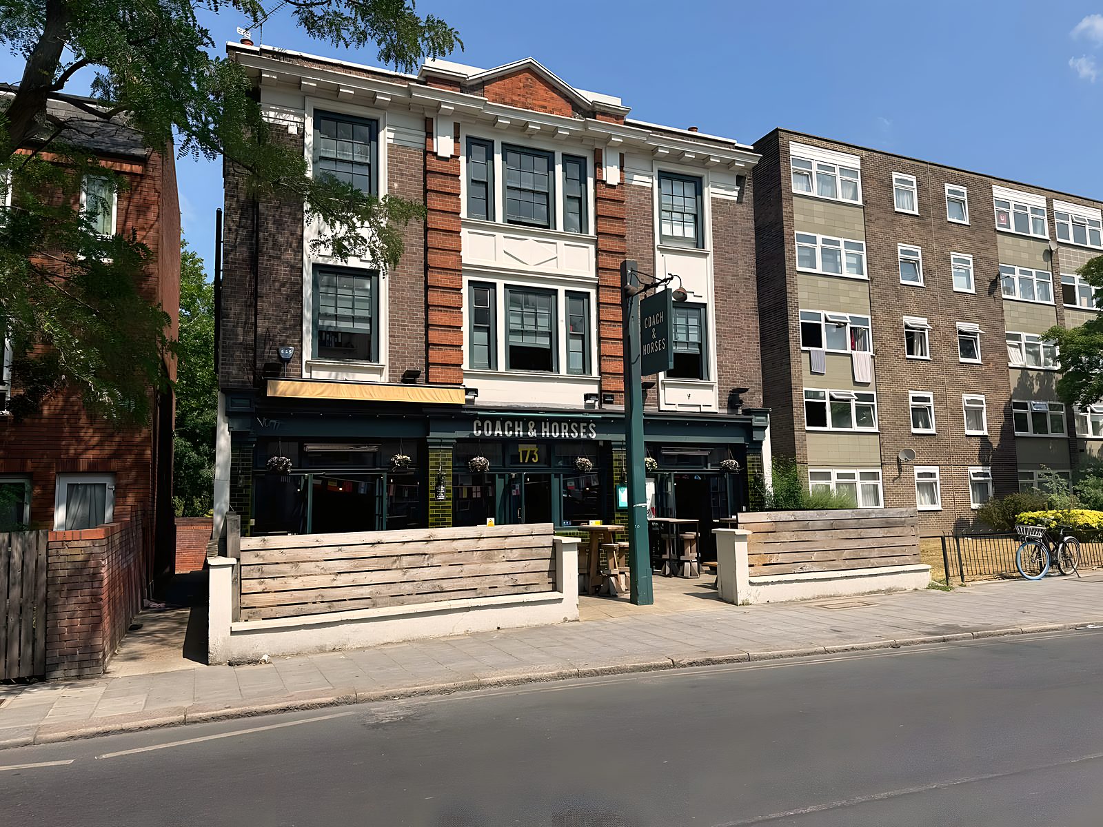 Wide view of the whole building from across Clapham Park Road with the projecting Coach & Horses sign